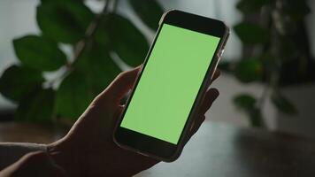 Pivoting around a hand holding a smart phone with green screen in shade video