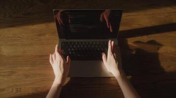 Top view of a caucasian woman hands typing code on a laptop computer in the sunset sunbeam video