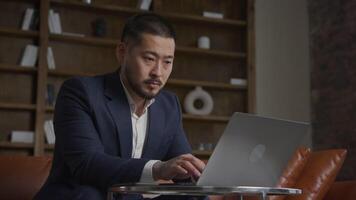 Asian man typing on laptop, businessman working on computer video