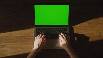 Woman hands resting on laptop computer keyboard with chromakey green screen and leaving the frame video