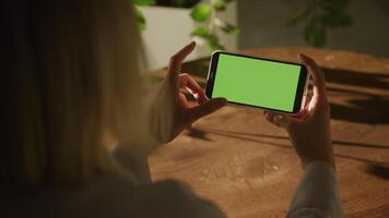 Handheld close up of caucasian woman holding smart phone with green screen and swiping left video