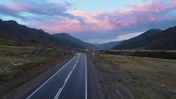 Aerial view of a valley with a river and road surrounded by mountains at sunset video