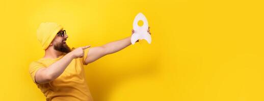 man pointing at rocket on yellow photo