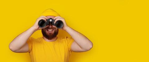 smiling man looking into binoculars panoramic photo