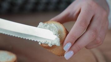 Spreading soft cheese on a slice of toasted bread, Close-up of a knife spreading soft cheese on a toasted bread slice. video