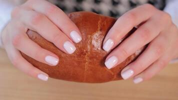 Close-up of hands holding a sliced bun filled with a rich, dark chocolate filling on a wooden surface video