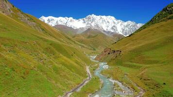 Aerial view of a river in a mountain valley against the backdrop of a snow-capped mountain range. video