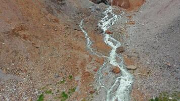 Drönare antal fot av en flod strömmande ut av en berg glaciär på en sommar dag. video