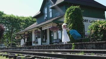 CN Fort Langley. Vintage train station girl spinning with suitcase in hands leather retro suitcase in her hands is spinning in the square against the background of an old building video