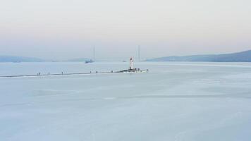 Flight over the frozen sea and drone view of Tokarevsky lighthouse at dawn video