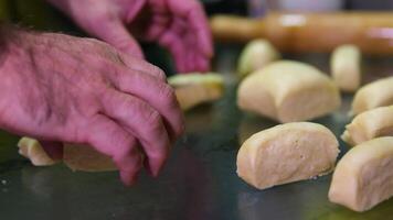 A batch of formed dough pieces on a table in the kitchen of a local bakery ready to bake. Olive ciabatta blanks laid out in a row in front of a large oven. Local bread production video