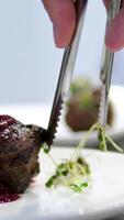 decorate meat with microgreens Chef makes dish presentation for serving. dish of roasted steak and baked sweet potato. Restaurant with professional gourmet cuisine. Public catering. video