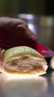 A batch of formed dough pieces on a table in the kitchen of a local bakery ready to bake. Olive ciabatta blanks laid out in a row in front of a large oven. Local bread production video