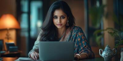 A woman in a sari is looking at a laptop photo