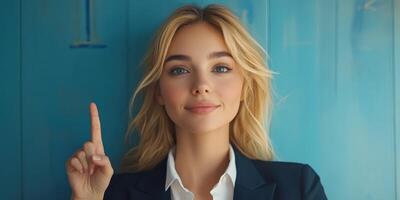 Confident young woman gestures with one finger while standing against a vibrant blue wall photo