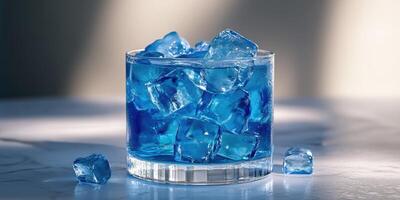 Refreshing blue beverage filled with ice cubes served in a glass on a bright surface photo