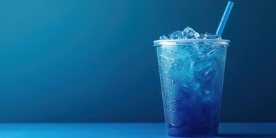 Refreshing blue drink with ice and a straw set against a dark blue backdrop photo
