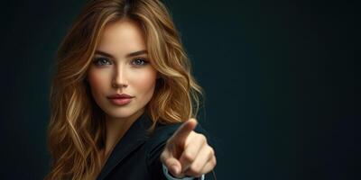 Model with long hair poses confidently in a dark studio while pointing directly at the camera during a fashion shoot photo