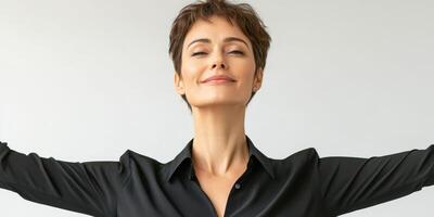 Confident woman smiling with arms outstretched against a neutral background in a studio setting photo