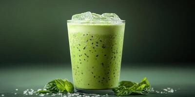 Refreshing green smoothie served in a glass with ice cubes, surrounded by mint leaves on a dark background photo