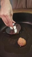 Round ball of minced chicken is placed on hot surface of a pan and pressed down to give it the desired shape, creating a patty. vertical video