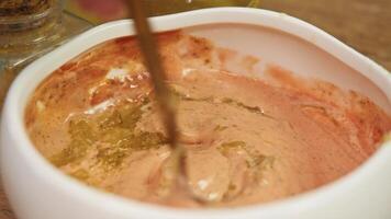 Delicious, juicy red burger sauce, based on mayonnaise, ketchup, and sour cream, with addition of pickled cucumber, is mixed in white bowl with spoon. video