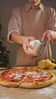 Baker starts to dust the base of an Italian pizza with tomatoes and grated cheese, continuing the baking process and allowing the cheese to melt. video
