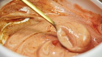 Cook combines rose red, homemade sauce with ketchup and mayonnaise, along with fresh seasonings, until it is smooth. He use spoon to mix ingredients in deep dish. close-up, macro video