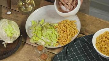 The chef adds tuna to a plate of corn salad, creating a traditional French dish known as the Nicoise salad. video
