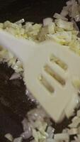 White onions are fried in boiling sunflower oil until they are soft and golden. They are then mixed thoroughly to ensure even cooking. video