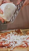 Chef sprinkles grated buffalo mozzarella cheese over base of pizza, allowing it to melt during cooking and create delicious, cheesy crust. video