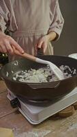 The onion, cut into thin slices, is stir-fried in boiling olive oil in frying pan on electric stove in the kitchen, in cozy and rustic atmosphere. video