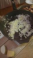 Onions, cut into small pieces, are poured with generous amount of olive oil and fried thoroughly during preparation of dish with cheese and mushrooms. video