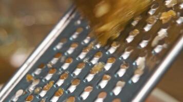 A close-up of process of grating a pickled cucumber on a metal grater with large holes. video