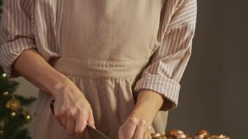 Young baker, wearing an apron and gloves, is preparing pasta with mushrooms using traditional Italian recipe. She carefully slices onions on cutting board, cutting them into small pieces. video