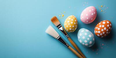Colorful decorated Easter eggs and paintbrushes on a blue background for spring festivities photo