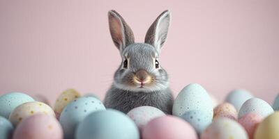 Cute gray rabbit surrounded by pastel Easter eggs on a soft pink background in a festive spring setting photo
