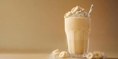 Creamy banana shake served in a tall glass with whipped cream and a straw on a warm beige background photo