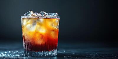 Refreshing cocktail with ice showcased on a dark surface, highlighting its rich amber color and textures photo