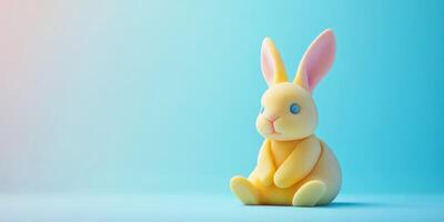 Cute yellow rabbit figurine sitting on a pastel blue background, perfect for spring decoration or themed events photo