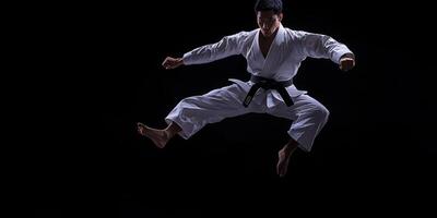 Martial artist performs an impressive jump kick in a dramatic studio setting during a training session at night photo