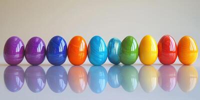 Colorful decorated eggs in a row reflecting on a smooth surface amidst a plain backdrop photo