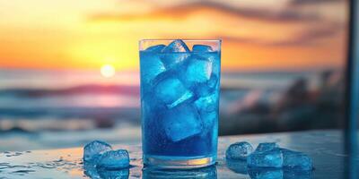 Refreshing blue drink with ice cubes at sunset by the beach photo