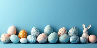 Colorful decorated eggs and a ceramic bunny arranged on a blue background for spring celebration photo