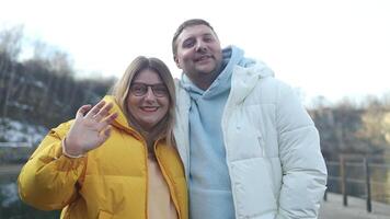 Portrait of happy Caucasian couple taking selfie photo, hugging and smiling at camera while posing together outdoors, enjoying hike in winter forest video