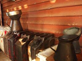 Old metal containers and jugs arranged against wooden wall, showcasing rustic charm photo
