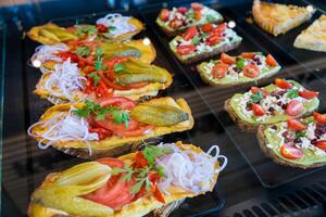 Assorted open-faced sandwiches with fresh toppings in a display case. photo