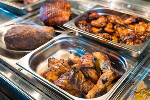 Grilled chicken drumsticks and wings in a buffet display photo