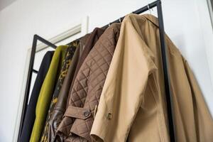 A row of autumn, spring coats in earthy tones hanging on a sleek clothing rack. Shooting from below photo