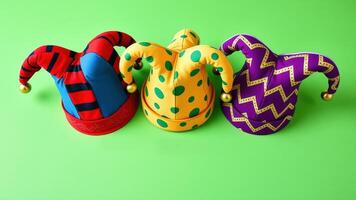 Three Colorful Jester Hats on a Bright Green Background photo